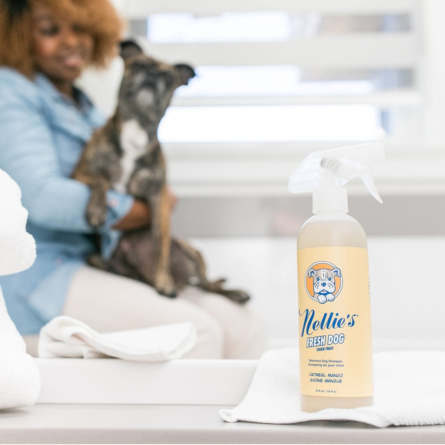 A lady holding her dog looking over to Nellie's Fresh Dog Shampoo -474 ml / 16 fl oz