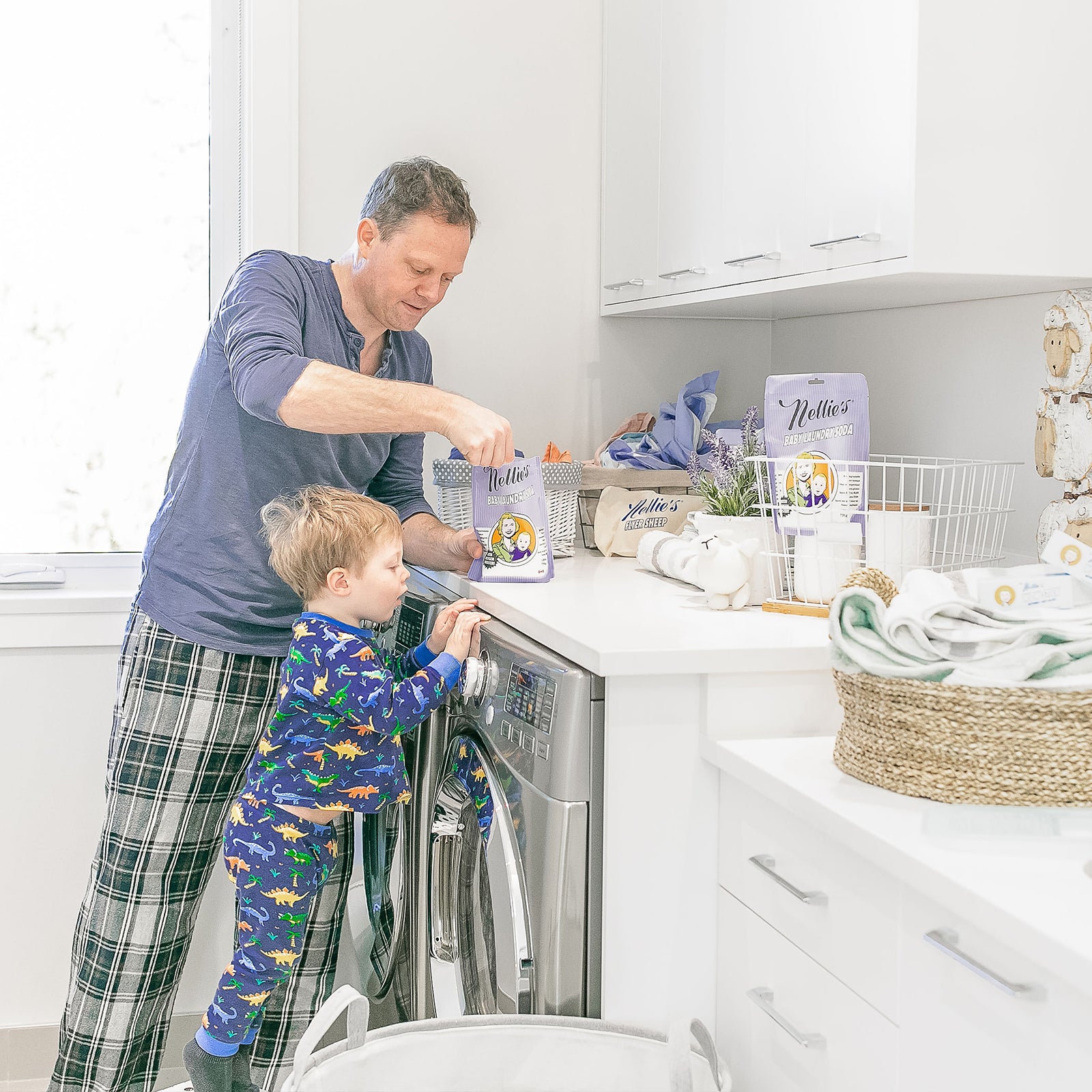 A Father in the Laundry Room scooping out Laundry Soda from Nellie's Baby Laundry Soda Pouch while his son is leaning forward to have a closer view 