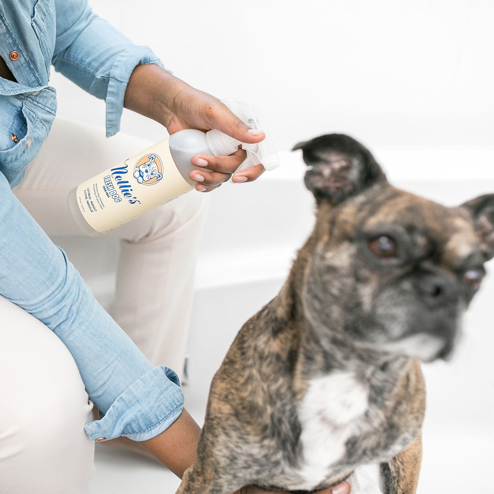 A lady spraying Nellie's Fresh Dog shampoo on her pet dog